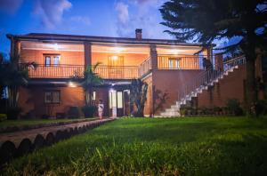 a woman standing in front of a house at night at Les Jardins d'Areca in Antsirabe