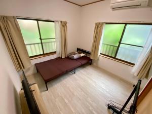 a small room with a bed and two windows at Guest House TETSU in Oshima