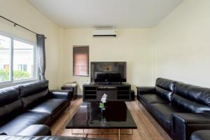 a living room with black leather furniture and a flat screen tv at Blue Lake Residences - Pattaya in Nong Prue