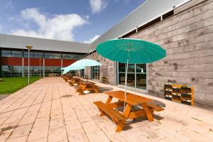 a row of benches with umbrellas in front of a building at Hotel Colombo in Vila do Porto