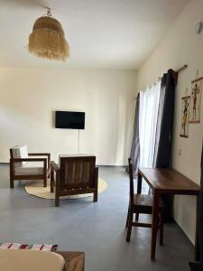 a living room with a table and chairs and a tv at Villa Soa in Nosy Be