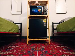 a room with two beds and a television on a shelf at Hee Pee hostel Buriram in Sathani Buriram