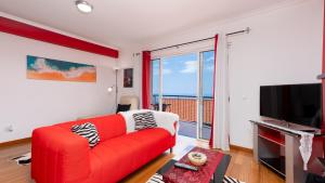 a living room with a red couch and a television at Cliff Refuge by LovelyStay in Santa Cruz