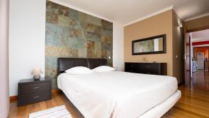 a bedroom with a white bed and a stone wall at Cliff Refuge by LovelyStay in Santa Cruz