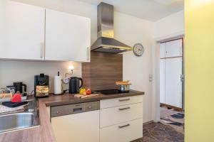 a kitchen with white cabinets and a clock on the wall at Apartmenthaus Baden-Chalet in Bühl