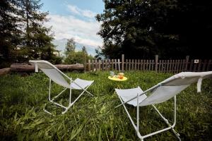 two white chairs and a table in the grass at Chalet Louchelet in Hérémence