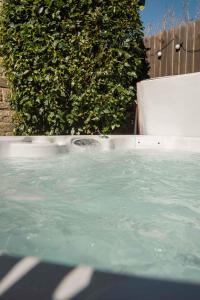 a hot tub with water in front of a hedge at Yorebridge House in Bainbridge