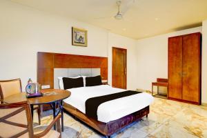 a bedroom with a large bed and a table at Townhouse JFN Comfort Hotel in Chennai