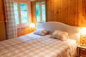 a bedroom with a bed with two pillows and two windows at Chalet Les Rhodos in Vex