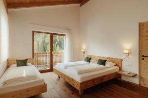 a bedroom with two beds and a window at New - Penthouse Zirm Untermairhof in Selva dei Molini