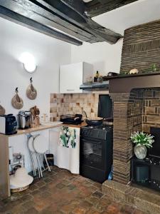 a kitchen with a stove and a brick fireplace at Cottage spirit in Normandy - typical studio in Évreux