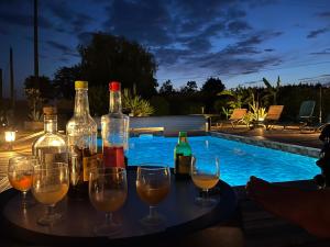 a table with wine bottles and wine glasses next to a swimming pool at chambre d'hôtes avec petit déjeuner compris à Mégrit in Mégrit