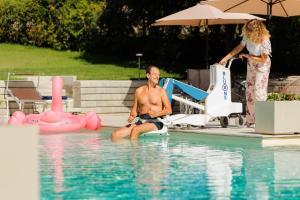 a man sitting in the water in a swimming pool at Bed & Breakfast L'Albero Maestro in Borgofranco dʼIvrea