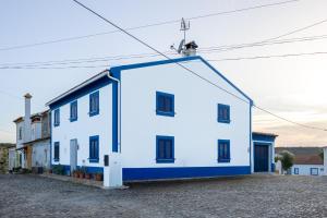 a white and blue building with black windows at Casa de Sume in Monte da Pedra