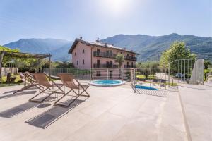 a patio with chairs and a house and mountains at Residence La Vigna in Arco