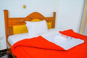 a bed with a red blanket and two white towels at KEFA Town Hotel in Kigali