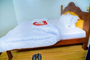 a bed with white sheets and a pair of shoes on it at KEFA Town Hotel in Kigali +6 photos