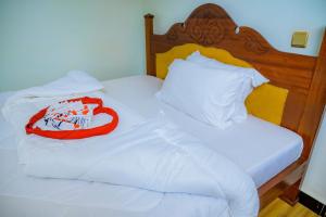 a white bed with a red blanket on it at KEFA Town Hotel in Kigali