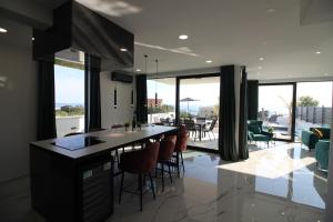 a kitchen with a counter with chairs and windows at Villa New York in Novalja