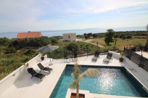 a house with a swimming pool with chairs and an umbrella at Villa New York in Novalja