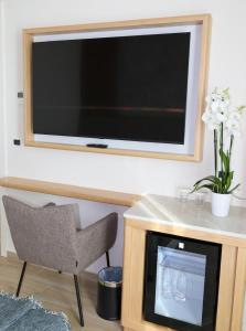ein Flachbildfernseher an der Wand, dazu ein Stuhl und ein weiterer Stuhl in der Unterkunft Avaris Hotel in Dhërmi
