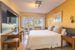ein Hotelzimmer mit Bett, Schreibtisch und Fernseher in der Unterkunft Hotel Las Rocas in Mar del Plata + 79 Fotos
