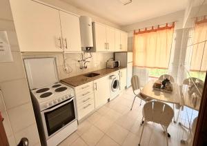 a kitchen with white cabinets and a table and a stove at Edificio Caique C in Armação de Pêra