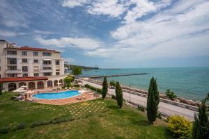 a building with a swimming pool next to the ocean at Apartments Poemia- sea view, Free Parking, complex Carpe Diem in Balchik