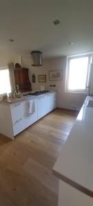 a kitchen with white cabinets and a wooden floor at Casa 33 in Gardone Riviera +23 photos