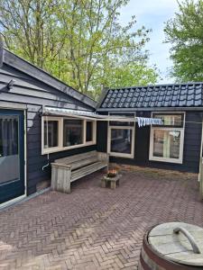a house with a bench on a brick patio at Guesthouse Bij Maud in Barsingerhorn