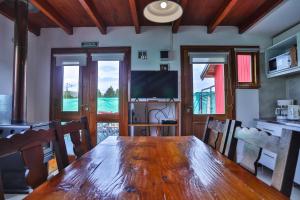 a dining room with a wooden table and a television at Complejo Casa Roja in Dina Huapi +31 photos