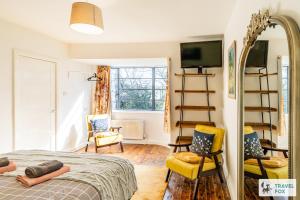 a bedroom with a bed and two chairs and a mirror at Springfield House in Cheadle