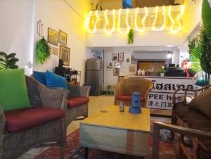 a living room with chairs and a table and a kitchen at Hee Pee hostel Buriram in Sathani Buriram