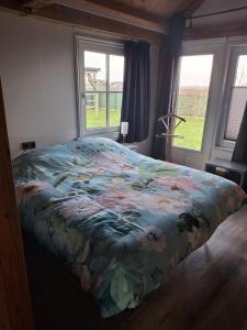 a bedroom with a bed with a floral blanket at Guesthouse Bij Maud in Barsingerhorn