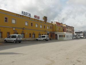 dos furgonetas blancas estacionadas frente a un edificio amarillo en Hostal Arias, en Zafra