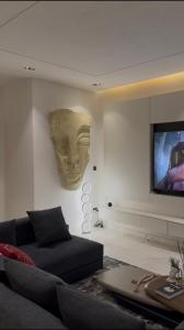 a living room with a couch and a flat screen tv at ZEELUX Apartment in Ikuata