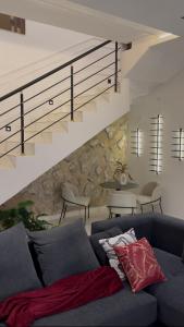 a living room with a blue couch and stairs at ZEELUX Apartment in Ikuata