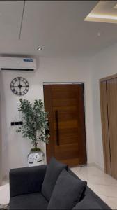 a living room with a couch and a clock on the wall at ZEELUX Apartment in Ikuata