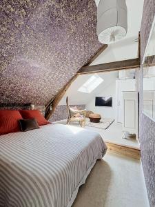 a attic bedroom with a bed and a table at Chambre d'hôtes Cocotte & Bigoudi in La Ferté-Beauharnais