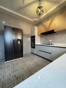 a kitchen with a stainless steel refrigerator and tile floor at Modern Three-Bedroom Apartment in Accra