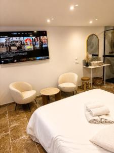 a bedroom with a bed and two chairs and a tv at Suite avec jacuzzi DOLCE NOTTE in Rochegude +14 photos