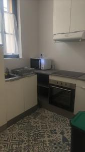 a kitchen with a stove and a sink and a microwave at Maison confort ombragé 2 chambres in Amélie-les-Bains-Palalda