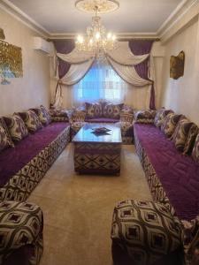 a living room with purple couches and a chandelier at App de luxe sur complexe ATANMIYA de MARTIL in Martil +1 photo