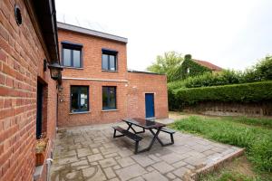 a patio with a picnic table in front of a brick building at De Ontspannerij in Lille