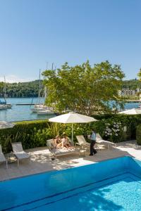 two people sitting under an umbrella next to a swimming pool at Bellerive Lifestyle Hotel in Salò