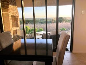a dining table and chairs in a room with a view at Olive Grove Addo in Addo +11 photos