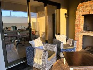 a living room with wicker chairs and a fireplace at Olive Grove Addo in Addo
