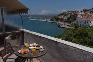 ein Tisch mit Speisen und Getränken auf einem Balkon mit Blick auf ein Gewässer in der Unterkunft Galaxy New Hotel in Pylos