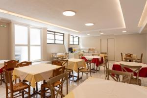 ein Esszimmer mit Tischen, Stühlen und Fenstern in der Unterkunft Galaxy New Hotel in Pylos