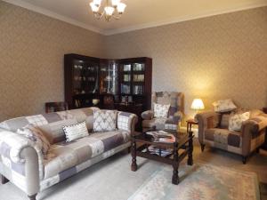 a living room with a couch and two chairs and a table at Sorbietrees B&B in Newcastleton